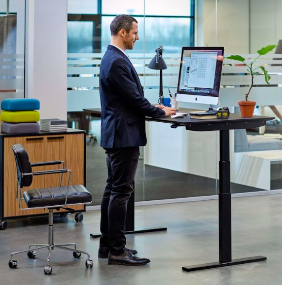 a Man Standing While Using a Computer Place at the Top of Standing Desk